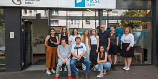 Eine Gruppe steht vor dem Eingang des PIKSL-Labors in Düsseldorf.