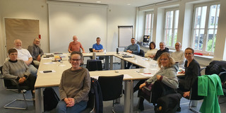 Participants in the workshop seminar “Co-determination 0.0” Photo: Eleven people are seated at tables arranged in a rectangle in a conference room.