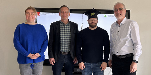 Photo: Four people are standing in a group.