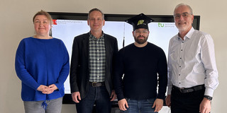 Photo: Four people are standing in a group.