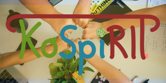 Several people bump their fists together in a team meeting over a table with laptops, notebooks, and plants. The logo “KoSpiRIT” is placed on top.