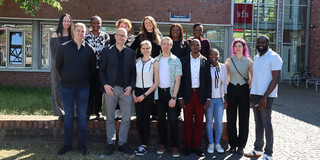 Group photo: 14 people standing in front of the sfs building