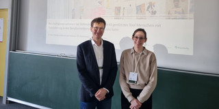 Prof. Dr. Bastian Pelka (links) und Lisa Preissner (rechts) stehen vor einer Präsentation in einem Seminarraum der Universität Bremen.