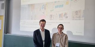 Prof. Dr. Bastian Pelka (left) and Lisa Preissner (right) are standing in front of a presentation in a seminar room at the University of Bremen.