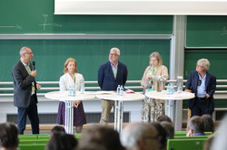 Foto: Podiumsdiskussion mit mehreren Personen in einem Hörsaal vor Publikum.