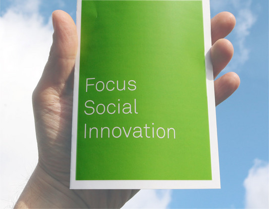 Hand die einen Flyer hält auf dem "Focus Social Innovation" steht.