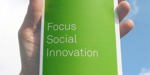 Hand die einen Flyer hält auf dem "Focus Social Innovation" steht.