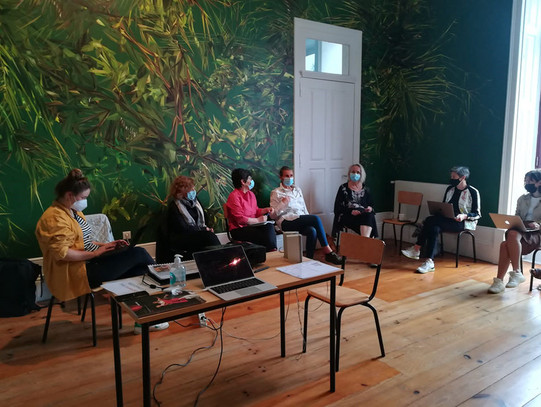 Foto von einem Meeting vom Projekt "ArtE – The Art of Employability" in Porto. Zu sehen sind sieben sitzende Teilnehmerinnen. Aufgrund der Corona-Pandemie tragen die Teilnehmerinnen einen Mund-Nasen-Schutz.