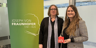 Photo: Lisa-Marian Schmidt and Christine Best standing next to a roll-up banner from the Fraunhofer Institute