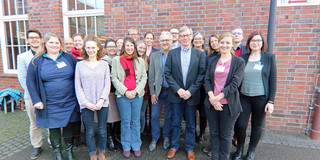 Foto: Eine Gruppe von Personen steht vor einem Backsteingebäude mit der Beschriftung „sfs“.