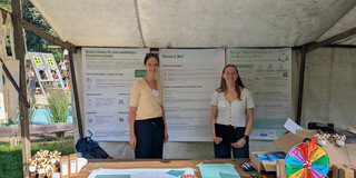 Das Foto zeigt Stephanie Bund und Sophie Sander am Präsentationsstand vor einigen Info-Plakaten
