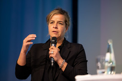 NRW-Wirtschaftsministerin Mona Neubauer bei der Podiumsdiskussion mit Mikrofon in der Hand