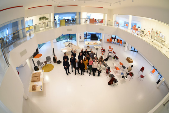 Group picture from above in the Design Factory Aveiro. The large room is bright, white and designed in modern architecture.