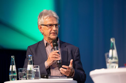 Prof. Dr. Jürgen Howaldt steht mit Mikrofon in der Hand an einem Stehtisch