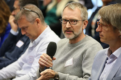 Eine Person im Publikum stellt eine Frage durch ein Mikrofon