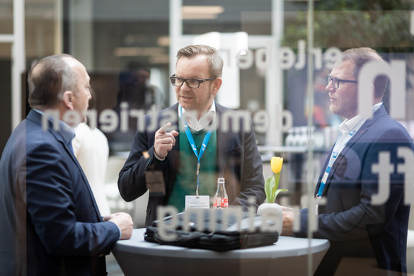 Foto einer Rede auf dem Aachener Dienstleistungsforum. Zu sehen sind drei Herren an einem Stehtisch, die sich unterhalten.