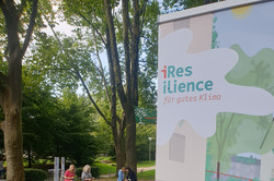 Klimaoase im Blücherpark in der Dortmunder Nordstadt mit Sitzgelegenheiten unter Bäumen und einem Schild vom Projekt "iResilience"