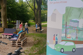 Klimaoase im Blücherpark in der Dortmunder Nordstadt mit Sitzgelegenheiten unter Bäumen und einem Schild vom Projekt "iResilience"
