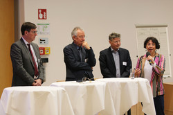 Vier Personen stehen an Tischen und diskutieren.