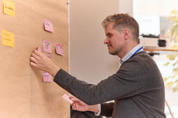 Daniel Krüger befestigt Notizzettel an eine Pinnwand.