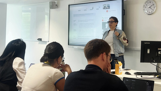 Foto: Dr. Katrin Bauer steht vor den Teilnehmenden und präsentiert auf einem Smartboard ihren Pretest