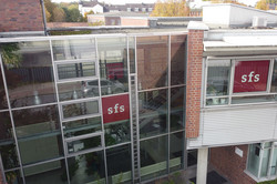 Drohnenaufnahme der verglasten Rückseite der Sozialforschungsstelle Dortmund an der Deutschen Straße in Eving mit zwei roten sfs-Logos