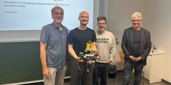 Vor einer Präsentation stehen von links nach rechts Prof. Dr. Johannes Weyer, Dr. Marlon Philipp, Prof. Dr. Bernd Sommer und Prof. Dr. Jürgen Howaldt.