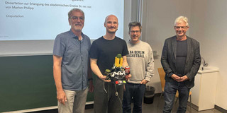 Vor einer Präsentation stehen von links nach rechts Prof. Dr. Johannes Weyer, Dr. Marlon Philipp, Prof. Dr. Bernd Sommer und Prof. Dr. Jürgen Howaldt.