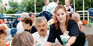 Ist das Normalarbeitsverhältnis inzwischen die Ausnahme? Menschen sitzen draußen an einem Eiscafé. Kellnerin bedient sie mit Eisbechern.