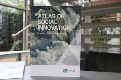 Atlas of Social Innovation Aufgestelltes Buch. Titel auf Englisch in Großbuchstaben „Atlas of Social Innovation". Untertitel auf Englisch in Großbuchstaben „ new practices for a better future".Buchcover: Ausschnitt der Erde aus dem Weltall fotografiert. Wolken. Dreiecksmuster mit dünnen weißen Linien im Vordergrund. Unten rechs: SI drive
